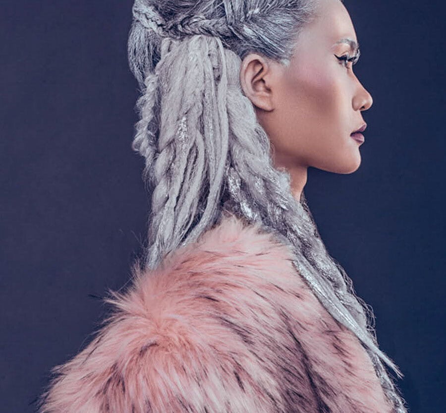 Close profile portrait of a fashion model with silver braided hair and a pink fur coat.