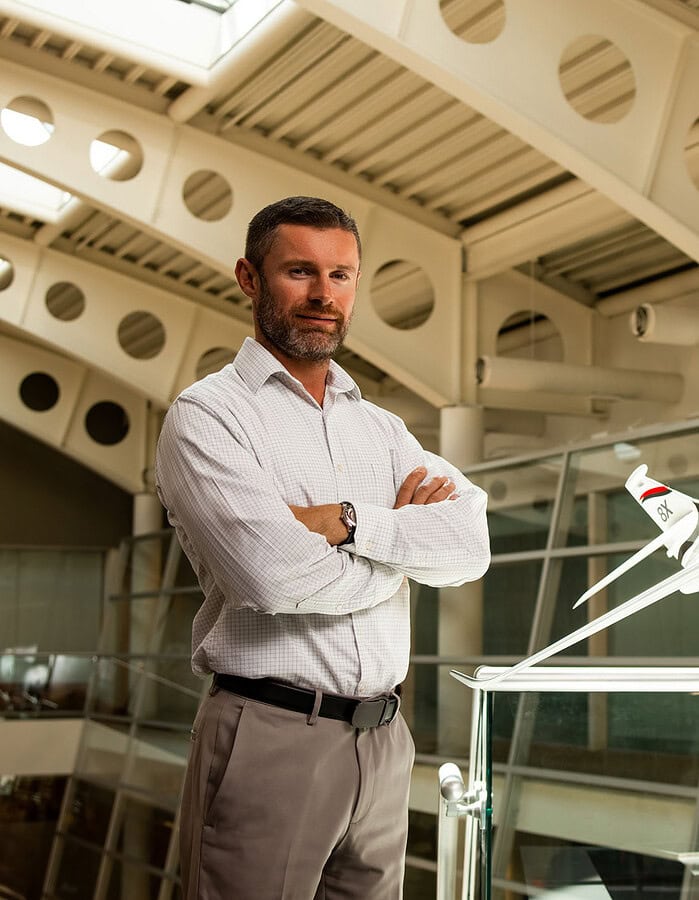 Aerospace professional standing beside a scale business jet in a modern corporate atrium.