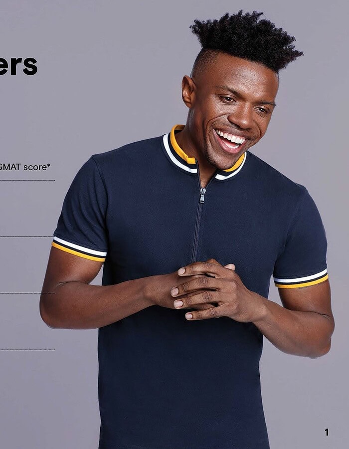 Smiling man in a dark polo shirt featured beside GMAT enrollment statistics in an advertising layout.