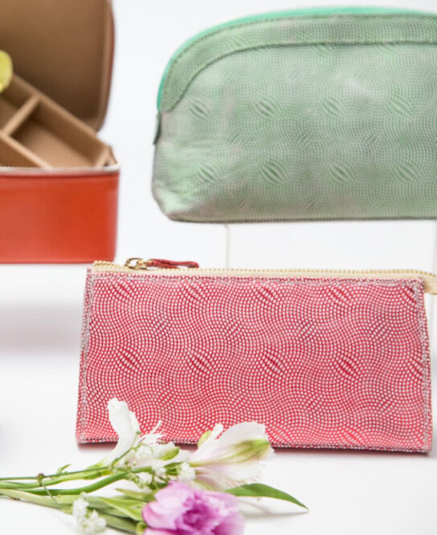 Colorful luxury leather accessory cases arranged with flowers in a bright studio still life.