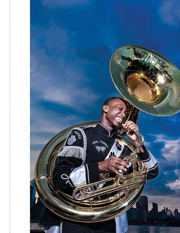 Marching band musicians with flute and sousaphone posed against a blue city skyline.
