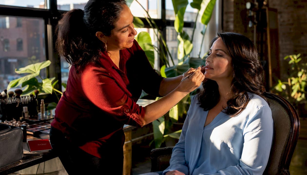 Makeup artist preparing client for studio headshot