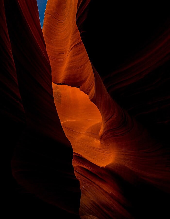Dark sandstone passage in Antelope Canyon glowing with orange reflected light.