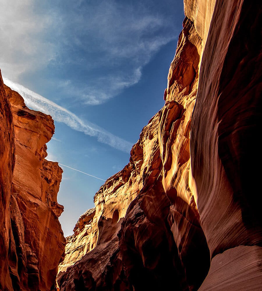 Red sandstone walls of Antelope Canyon opening toward a blue desert sky.