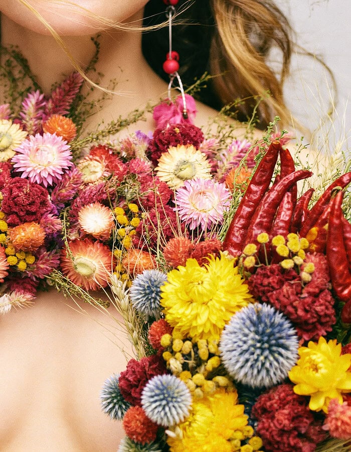 Close detail of floral styling with bright flowers and red peppers across the body.