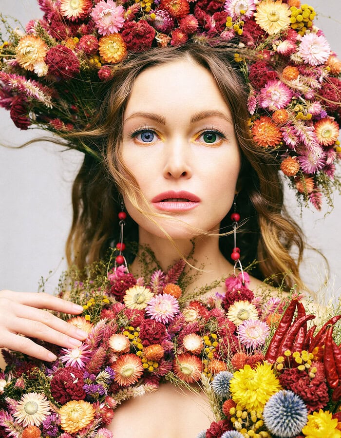 Close beauty portrait of a model surrounded by a colorful floral crown and floral styling.