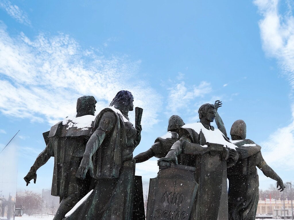 Snow-covered bronze figures of a Moscow war monument under a bright blue winter sky.