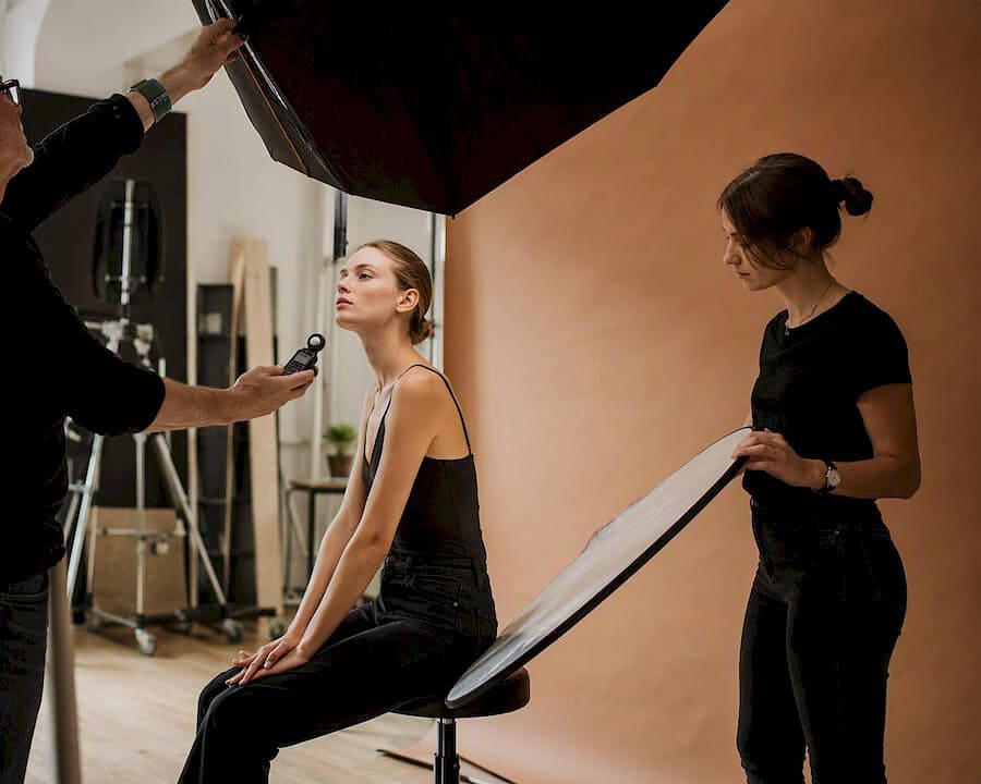Photographer adjusting lighting with fashion model in studio