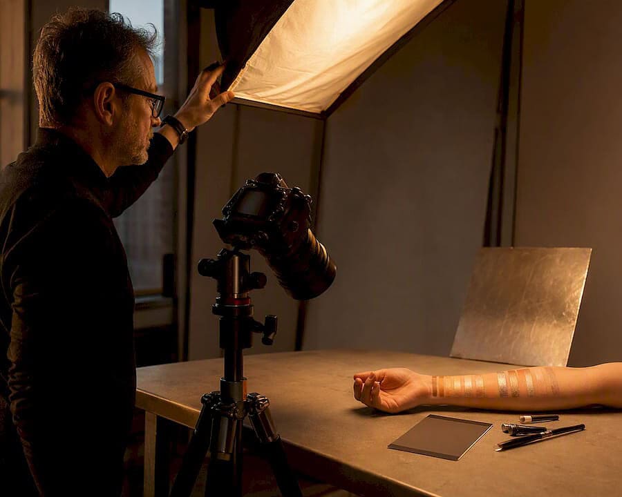 Photographer adjusting light over cosmetics swatch
