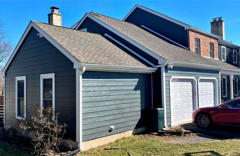 Modern blue house with attached garage and driveway in a residential neighborhood.