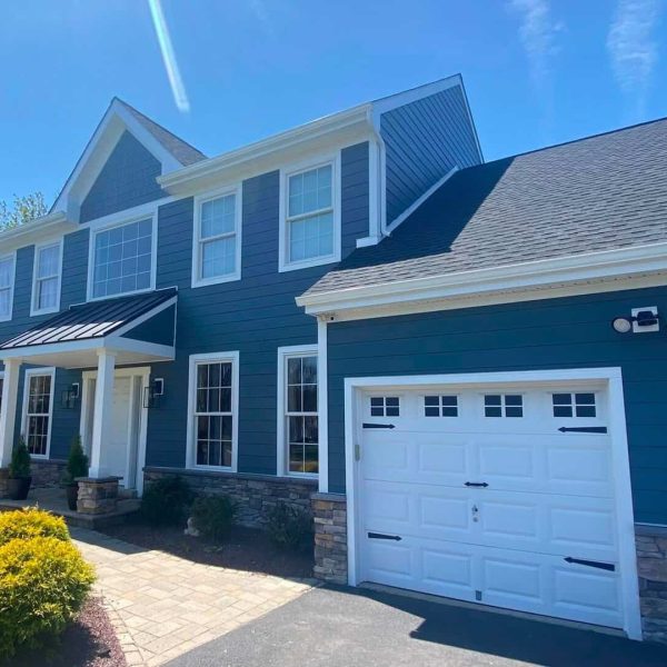 Beautiful blue house with white trim, stone accents, and a spacious garage.