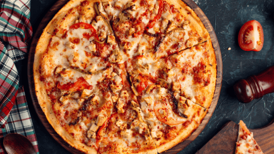 Freshly baked pizza with toppings on a wooden board, perfect for catering and events in the UK.