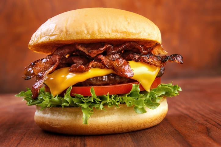 Crispy bacon cheeseburger with fresh lettuce, tomato, and melted cheddar on a soft bun.