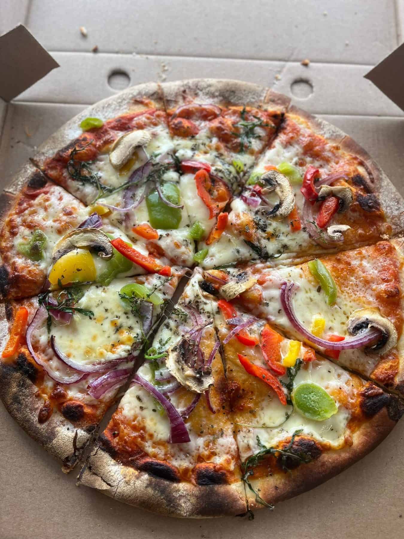 Fresh vegetable pizza with cheese, mushrooms, peppers, onions, and herbs from KK Catering.