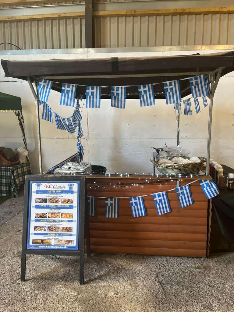 Greek flags and food stall at outdoor catering event in the UK.