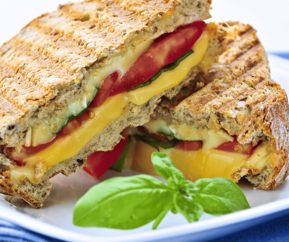 Freshly prepared toasted sandwich with melted cheese, tomatoes, and basil - ideal for catering.