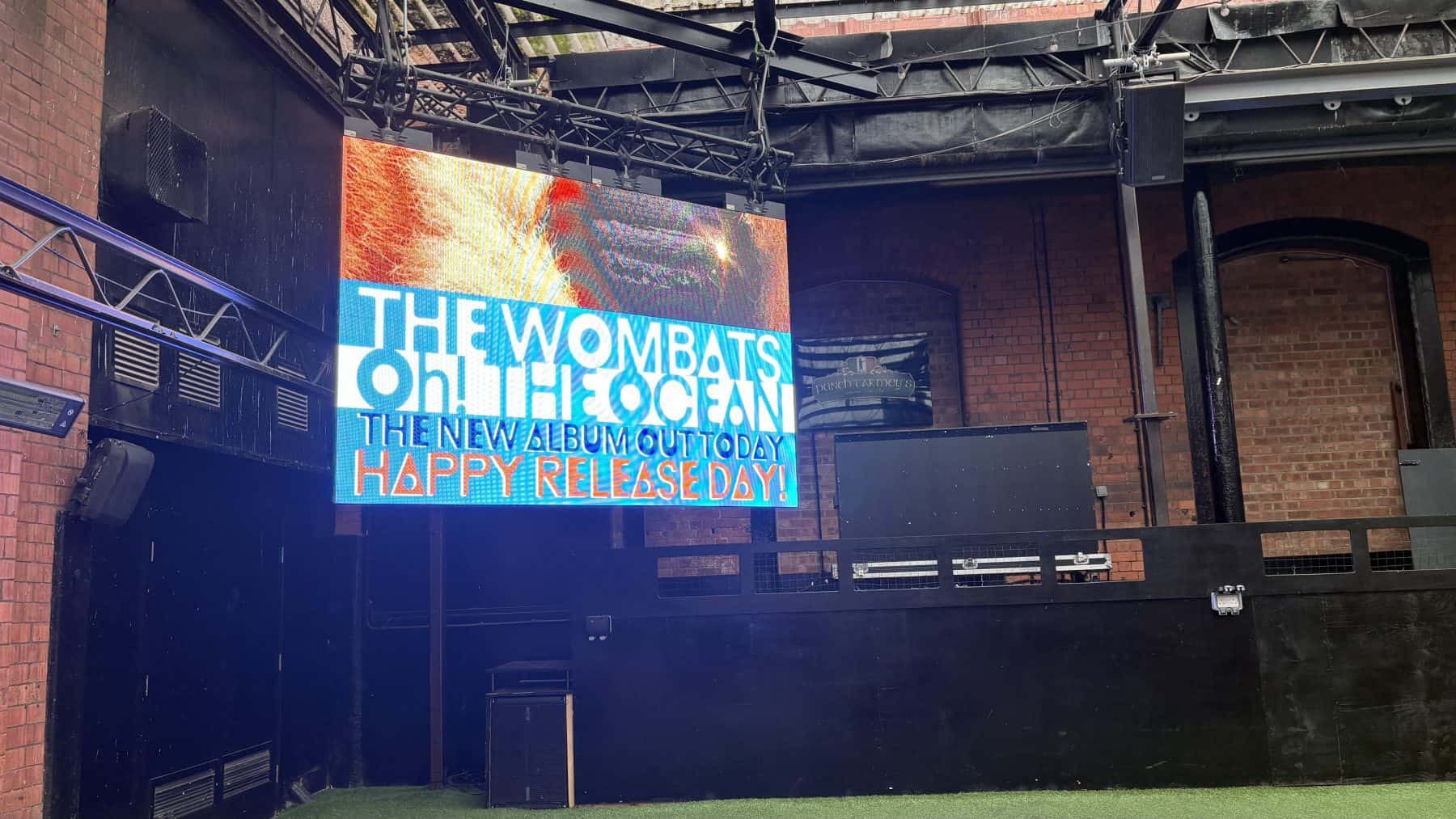 High-quality LED screen displaying live concert and album promotion at an indoor event space.