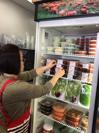 Meat shops in Koreatown are seeking better sales by increasing the number of non-meat items at their businesses. Shin Sun Meat owner Keum-sook Joo is organizing the side dish items at her shop.