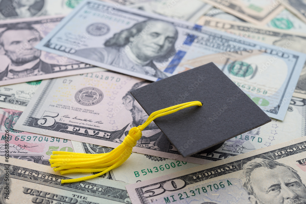 Graduation cap university or college degree on US dollars banknotes background. Education expense budget plan of money saving, loan, debt, personal loan, scholarship for studying abroad concept.