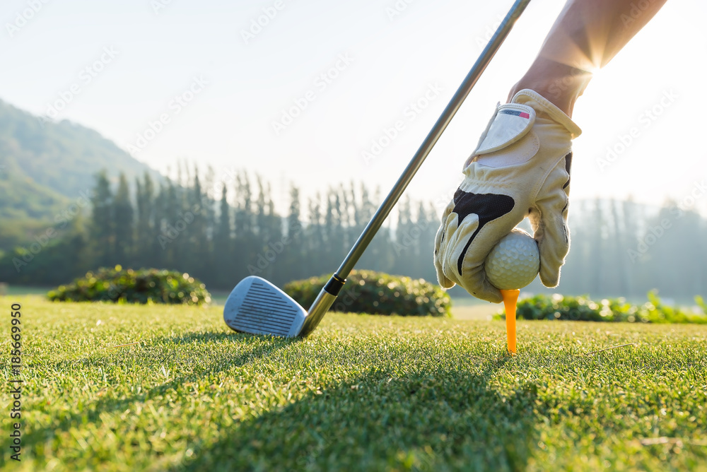 Hand hold golf ball with tee on course, tee off