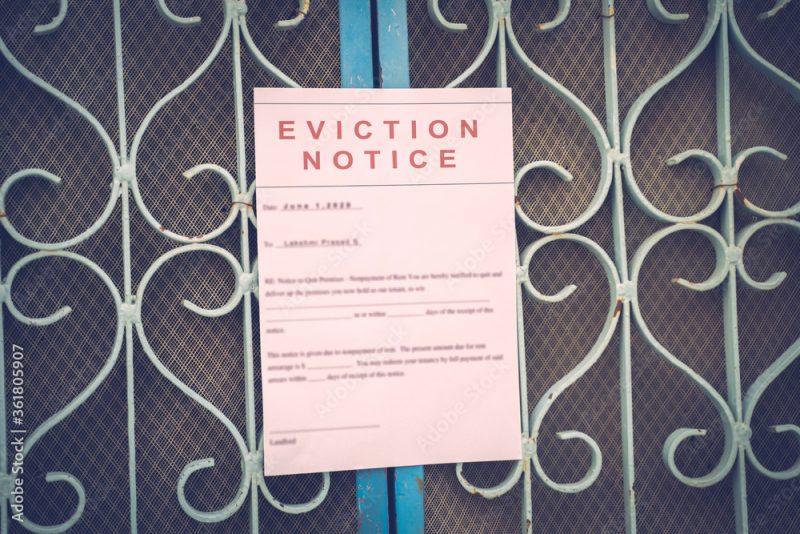 Foreclosed or eviciton notice on a main door with blurred details of a house with vintage filter.