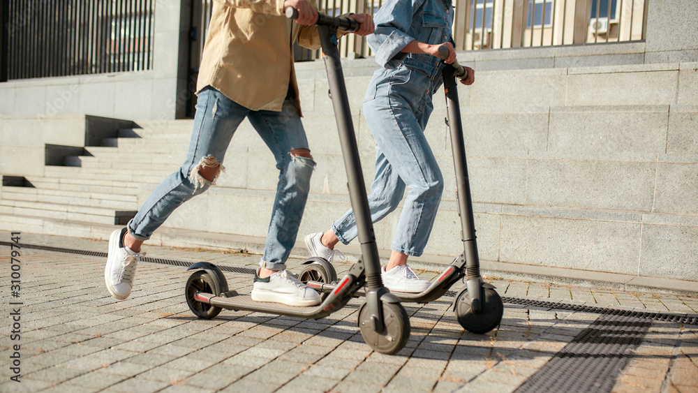 Lets ride. Girl and boy having fun driving electric scooters on a sunny day