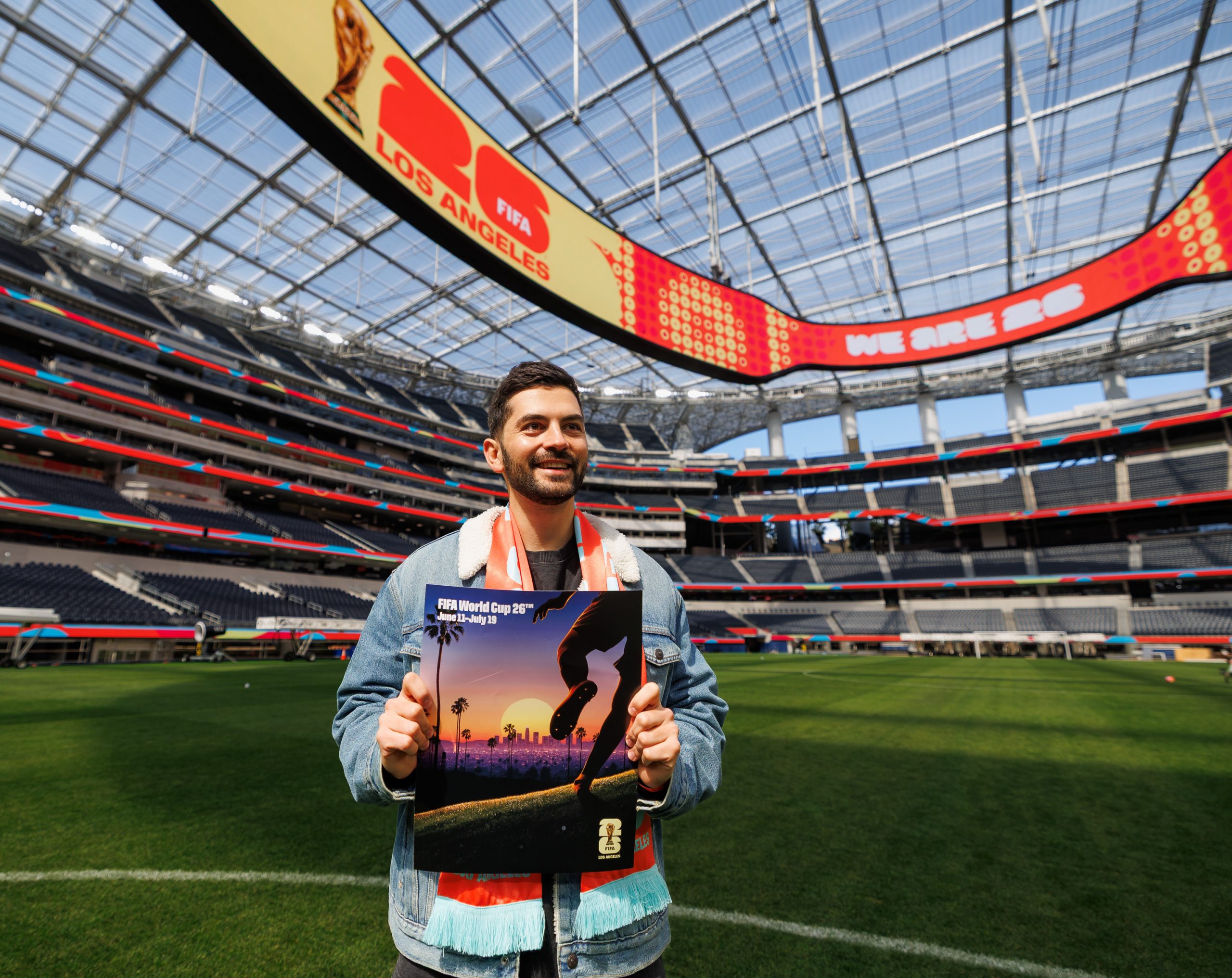 Thieb Delaporte-Richard holds the official Los Angeles World Cup poster at SoFi Stadium, where FIFA 2026 matches will take place.