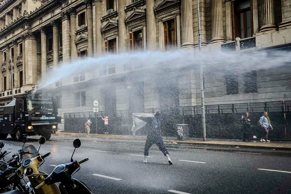 Protester waves Argentine flag during Javier Milei’s reform protest.