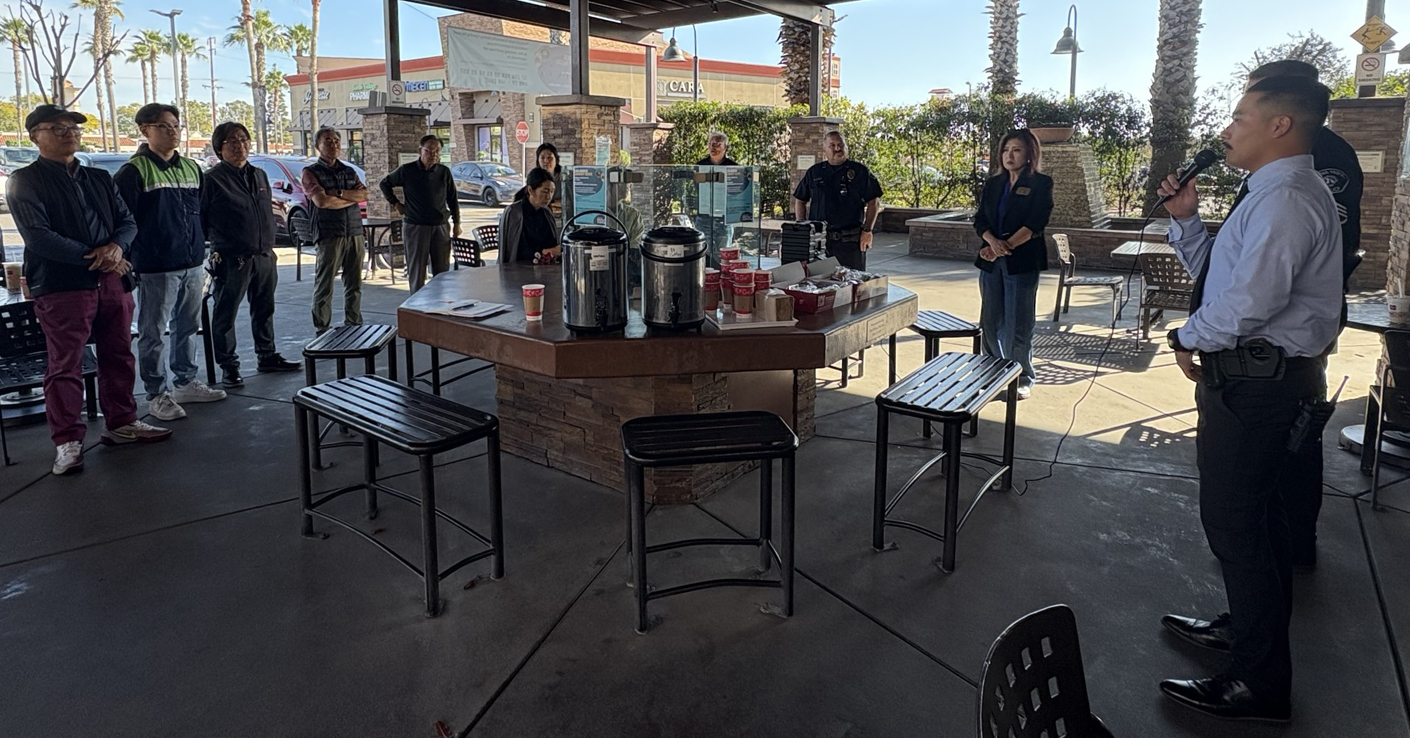 Detective Daniel Yeo speaking at a Buena Park public safety meeting about ongoing burglary investigations, with officials and police in attendance.