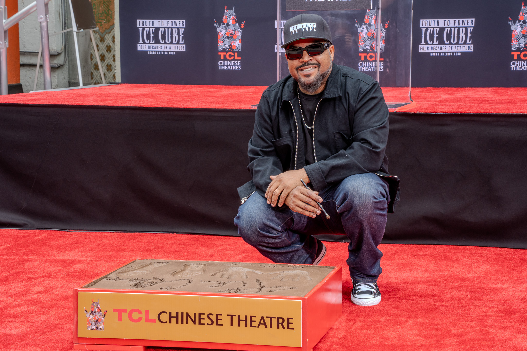 Ice Cube crouches by handprint at TCL Chinese Theatre