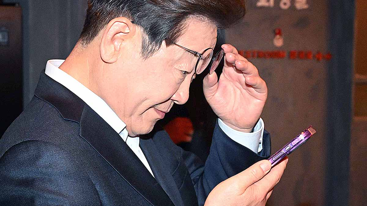 Former Democratic Party leader Lee Jae-myung looks at his phone after meeting with workers in Jongno District, central Seoul, on May 1. [JOONGANG ILBO]