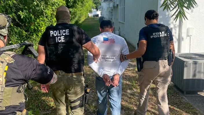 ICE agents detain a person during a deportation warrant crackdown