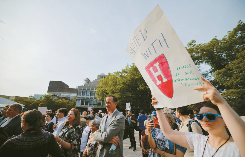 Person holds protest sign at Harvard Stand United rally in Cambridge amid Harvard DEI conflict
