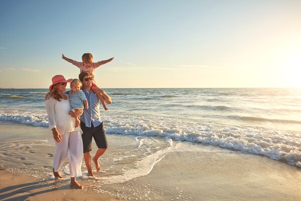 Family walking on a beach during summer vacation, reflecting U.S. summer vacation survey trends