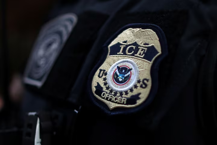 ICE officer's uniform with badge visible on shoulder, representing rapid deportation enforcement