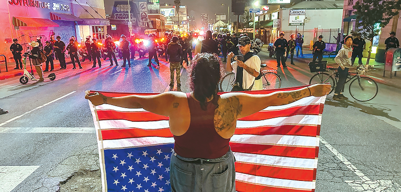Protester holds upside-down U.S. flag in silent demonstration at Koreatown intersection during LA march