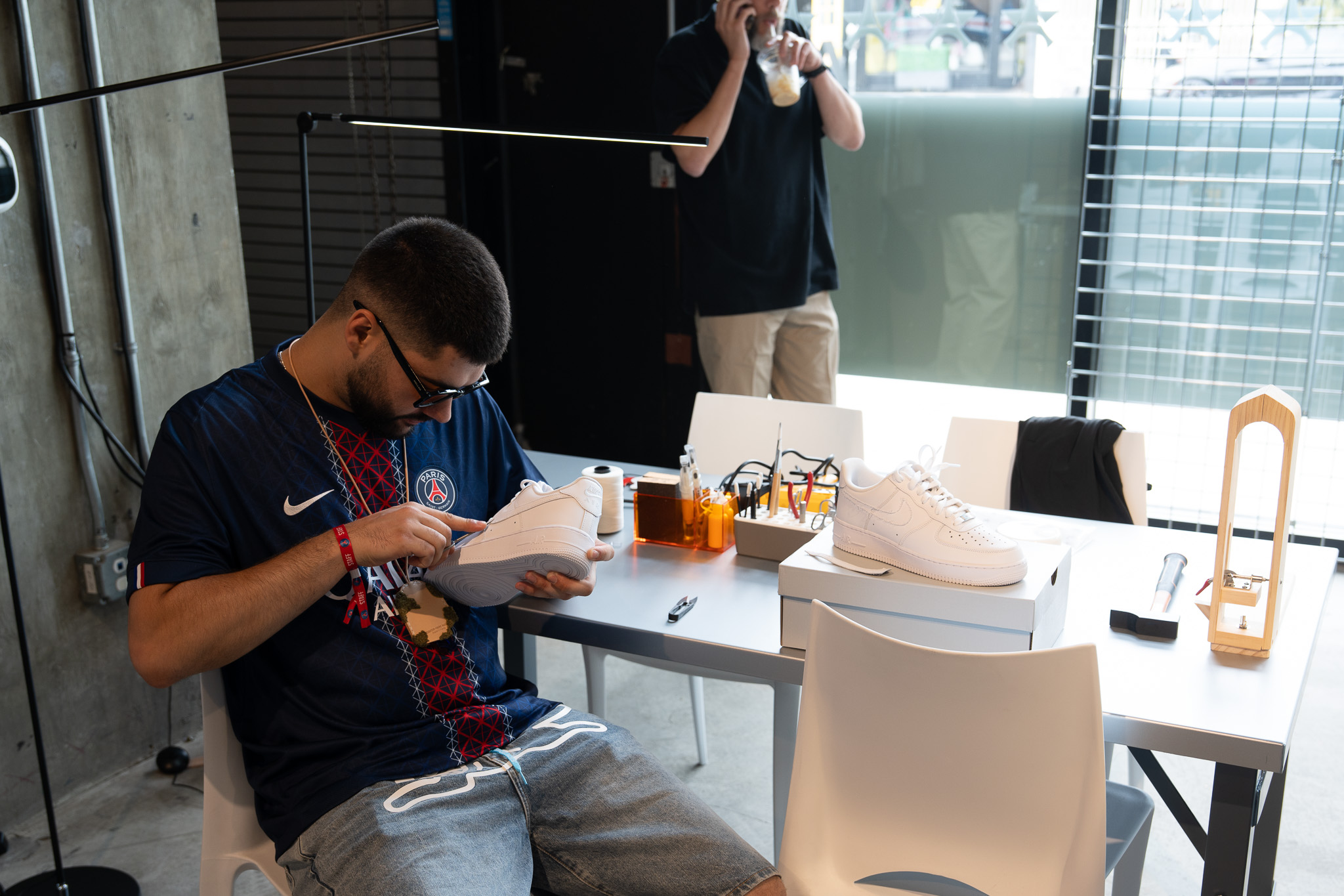 PSG House workshop staff examines sneaker during customization at LA pop-up