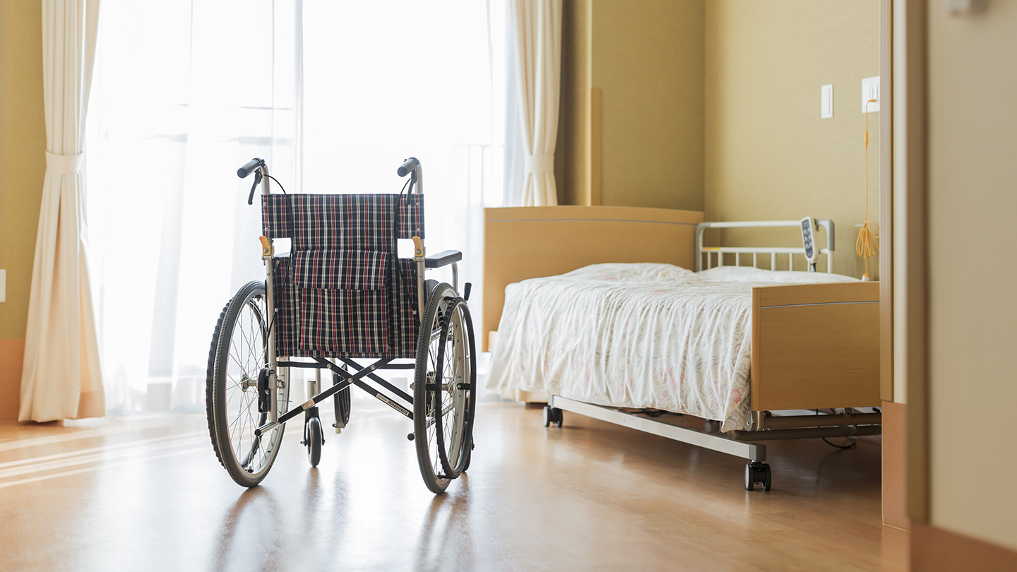 Wheelchair and hospital bed in a room highlighting nursing home conditions in California