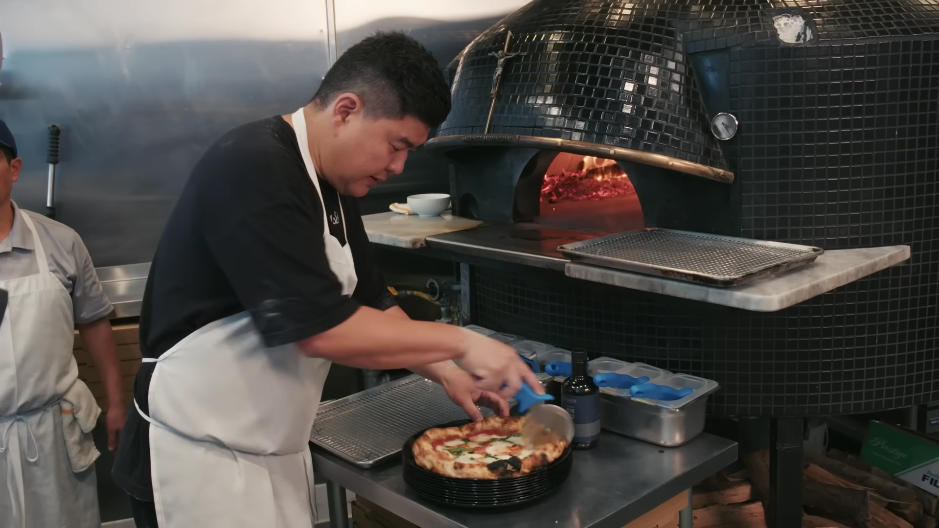 William Joo cutting pizza at Pizzeria Sei for Bon Appétit video