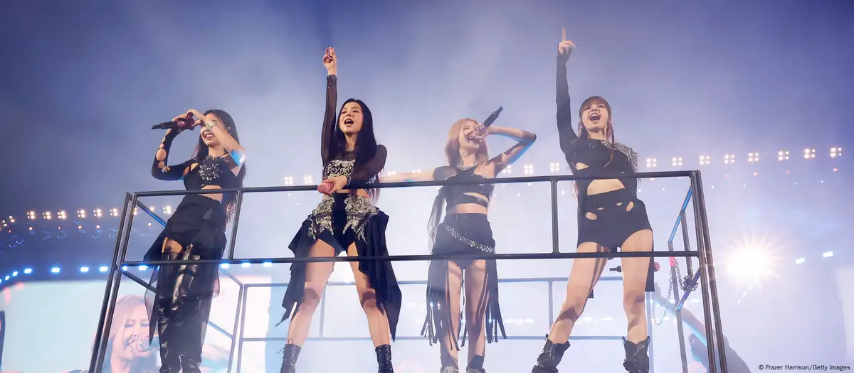 BLACKPINK on a lift surrounded by bright white lights creating a dreamlike concert atmosphere