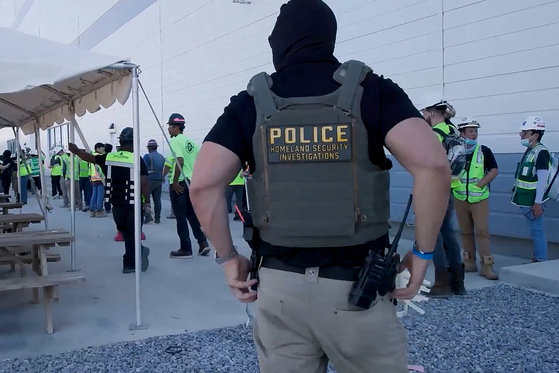 A masked federal agent wearing a Homeland Security Investigations vest guards a site during a raid where about 300 Koreans were among 475 people arrested at the site of a $4.3 billion project by Hyundai Motor and LG Energy Solution to build batteries for electric cars in Ellabell, Georgia on Sept. 4. [REUTERS]