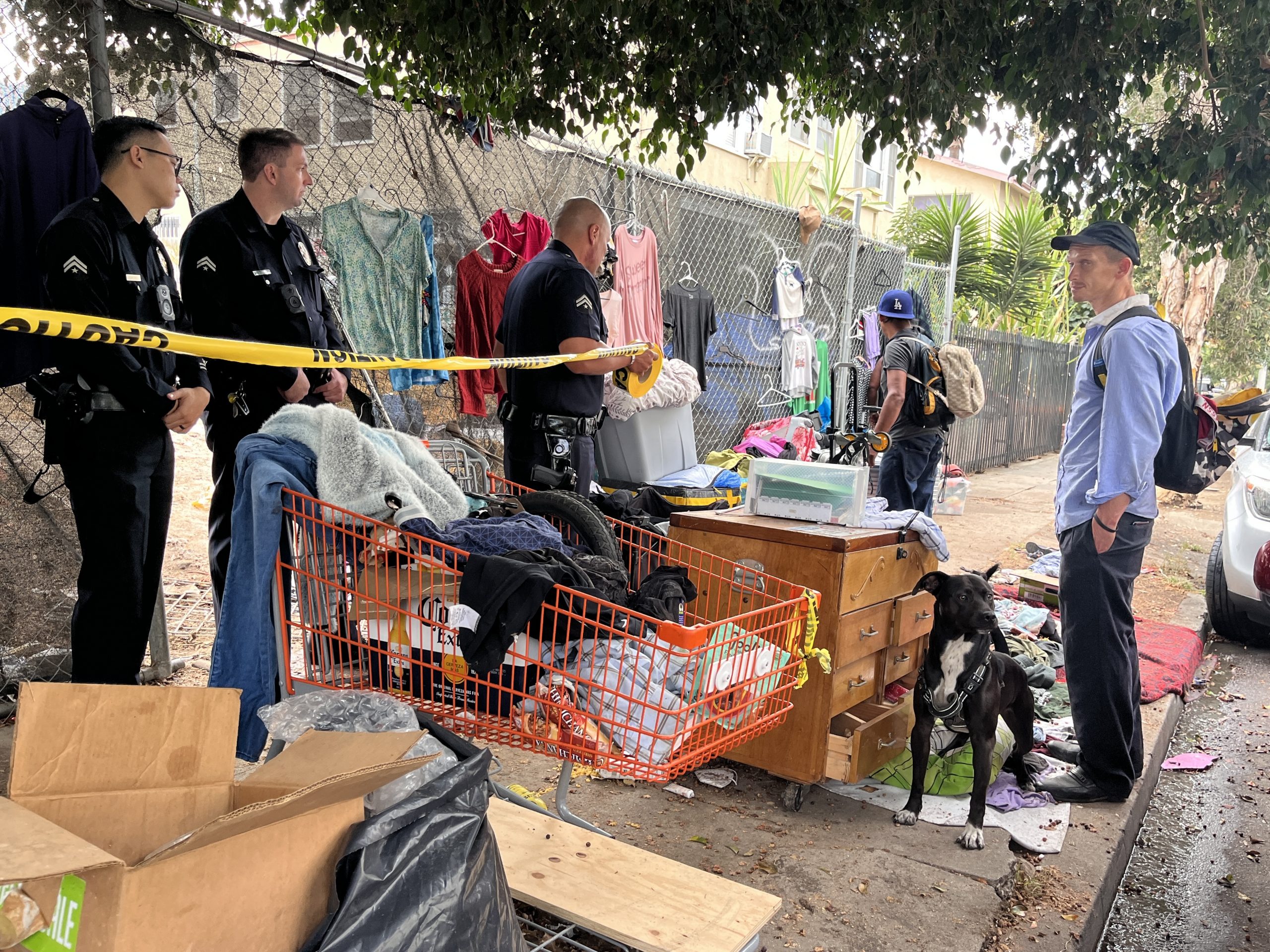 LAPD officers block access during Koreatown homeless encampment removal as a resident gathers belongings