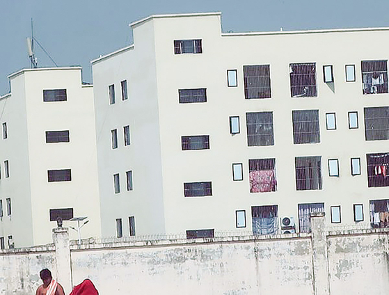 Buildings and guard posts suspected of being used by a criminal organization in Cambodia. Behind tall concrete walls topped with triple-layered barbed wire and sharp metal fragments, barred windows are visible, suggesting a heavily fortified compound. [AMNESTY INTERNATIONAL]