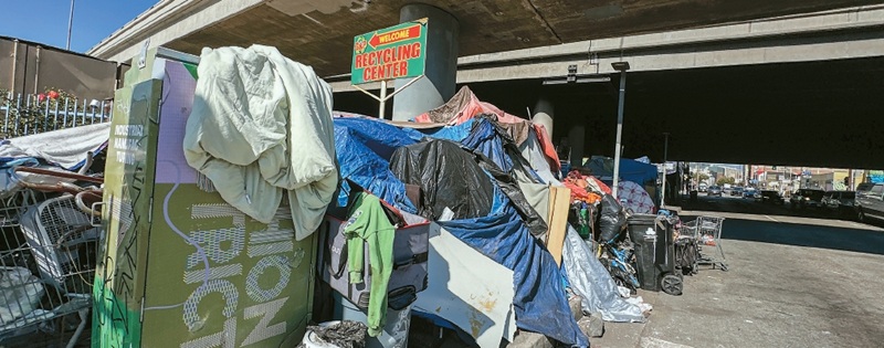 A homeless encampment has formed beneath the 10 Freeway near 17th Street in downtown Los Angeles. Dozens of people currently live along the road in front of a nearby recycling center, where tents stretch for several blocks. [Sangjin Kim, The Korea Daily]