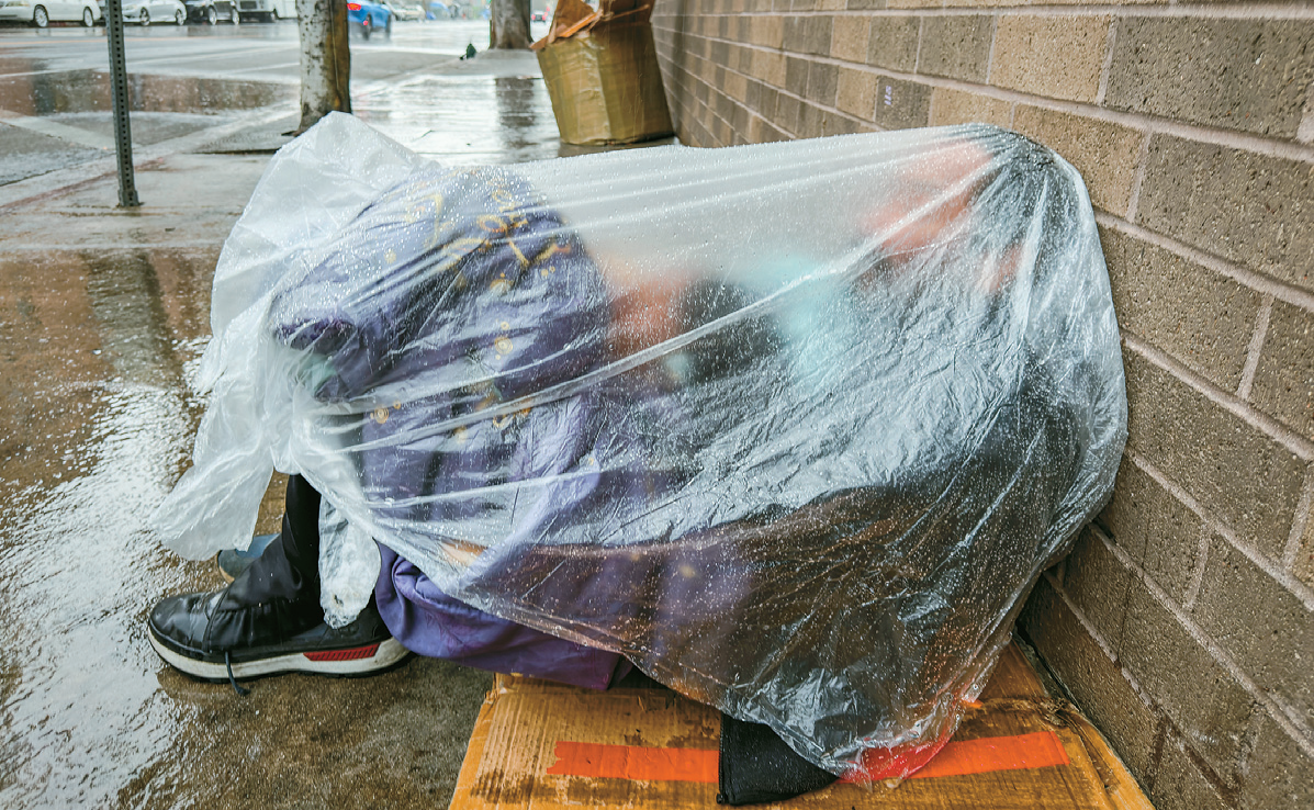 LA winter storm homeless man covering himself with plastic in Skid Row on the 20th