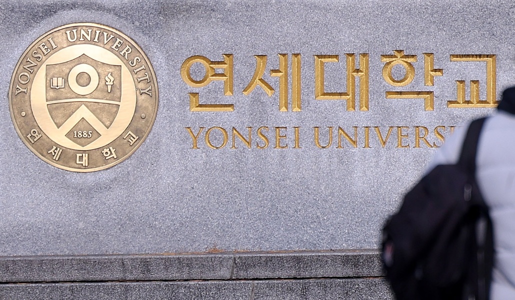 A pedestrian walks by a plaque of Yonsei University in western Seoul. [YONHAP]