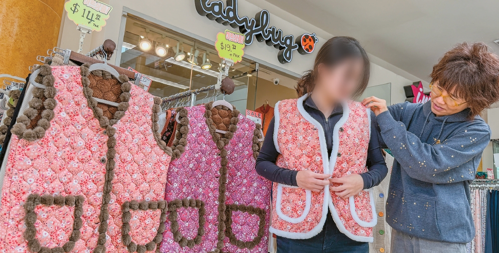 Korean woman trying on a kimjang vest trend item at a Korean clothing store inside Galleria Mall