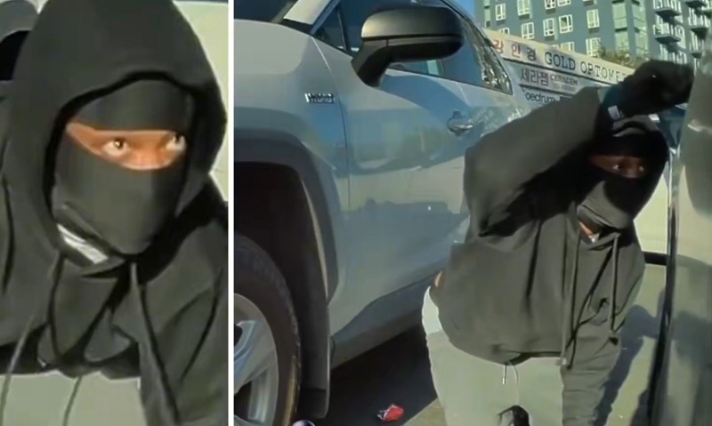 A robbery suspect is seen crouching as he opens the passenger-side door, captured on the victim’s dashcam footage. [ABC7 screenshot]