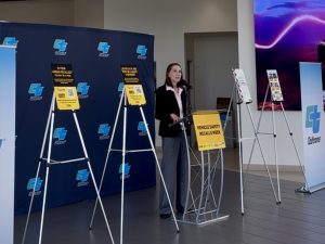 OTS Director Stephanie Dougherty speaking at a podium during a vehicle safety recall press conference in Los Angeles.