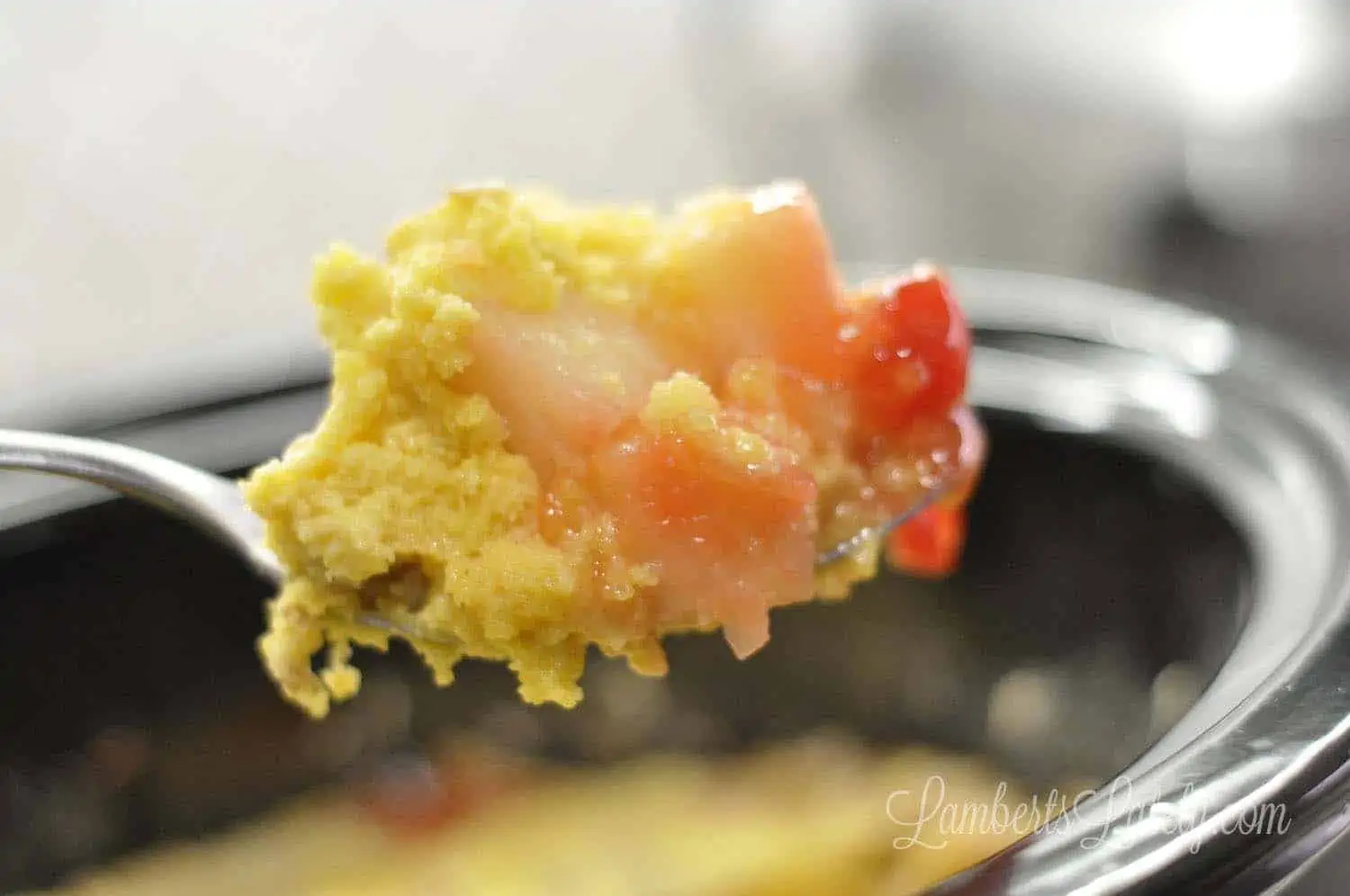 spoon of tropical dump cake with cherries and other fruits.